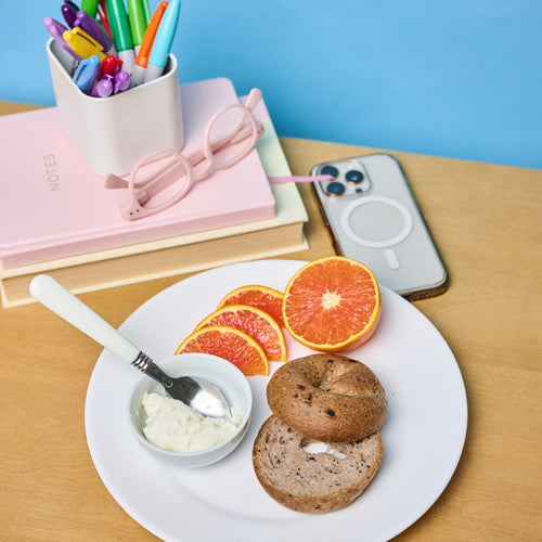 Gluten Free Bagel with cream cheese and fruit on a desk