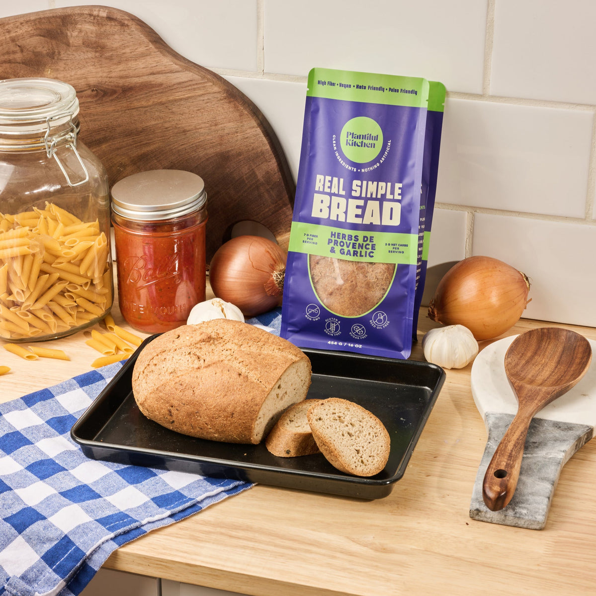 Gluten Free Loaf of bread flavored with Garlic and Herbs de Provence on the counter with tomato sauce and pasta, onions and garlic