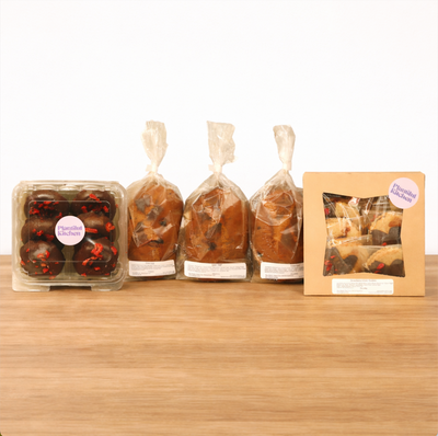 Baked goods including cookies and bread on a table with red flowers and a decorative stand.