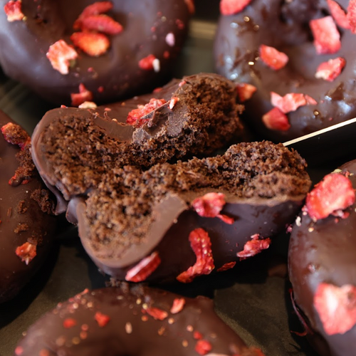 Chocolate donuts with strawberry pieces on a dark surface